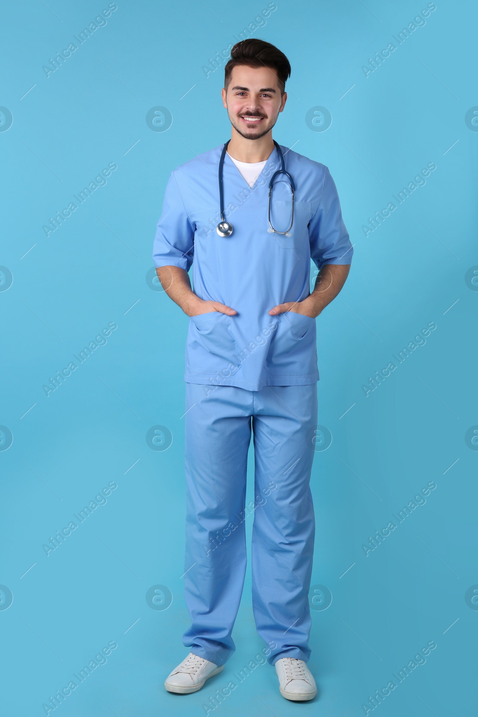 Photo of Young medical student in uniform on color background