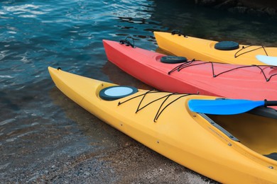 Photo of Modern kayaks with paddles on beach near river. Summer camp activity