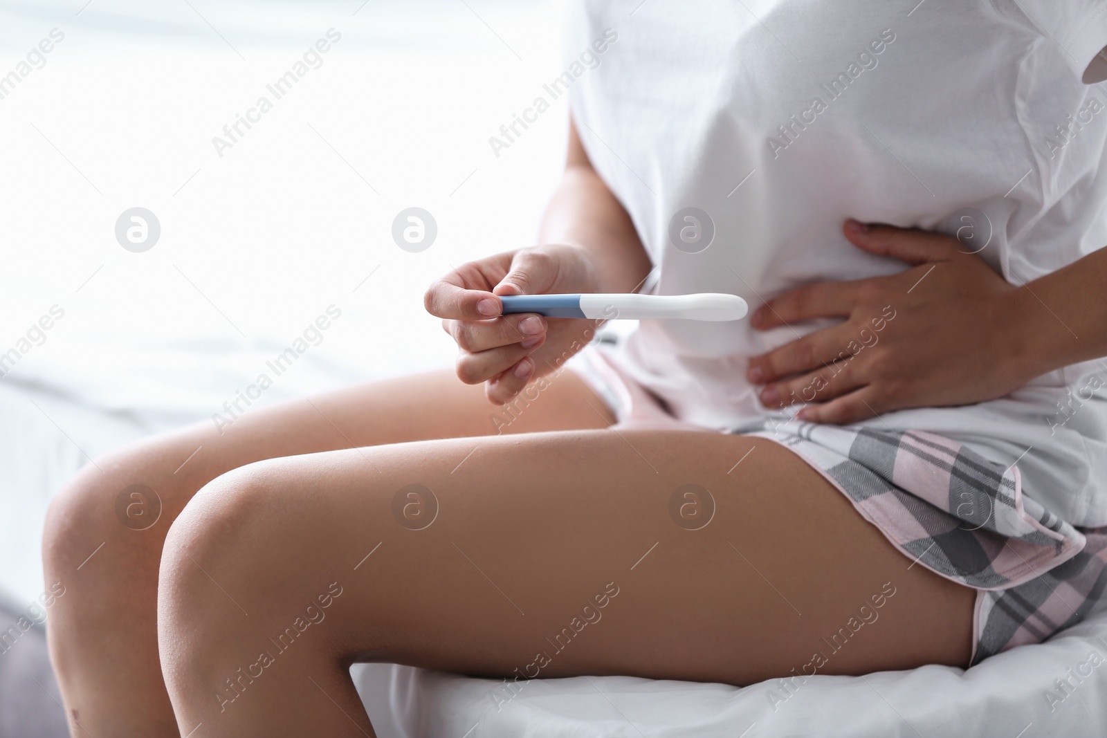 Photo of Young woman with pregnancy test in bedroom. Gynecology