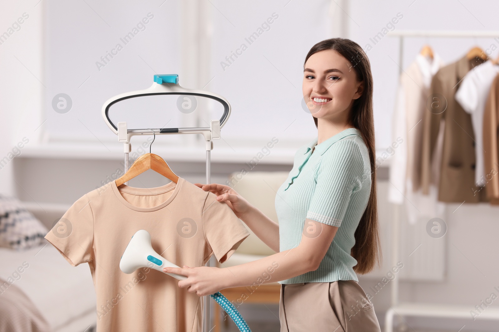 Photo of Woman steaming shirt on hanger at home