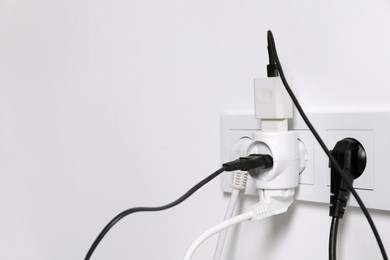 Many different electrical power plugs in sockets on light wall, space for text