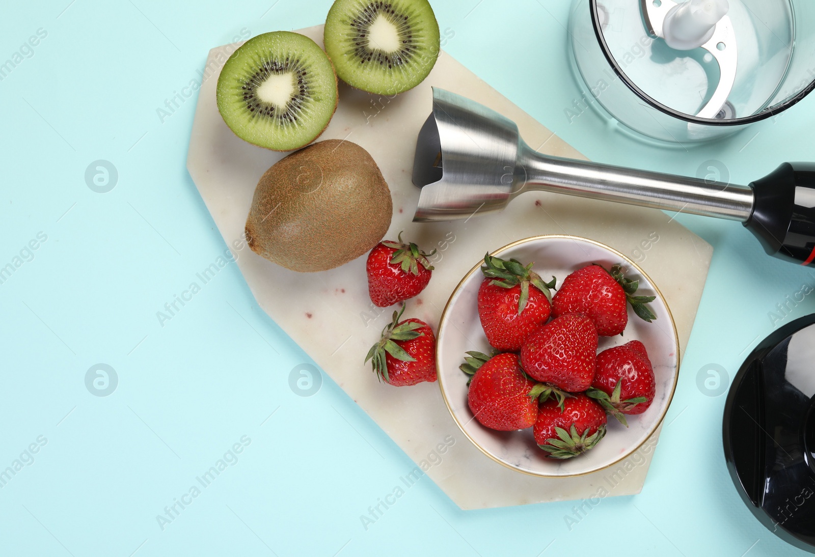 Photo of Hand blender kit and fresh fruits on light blue background, top view. Space for text