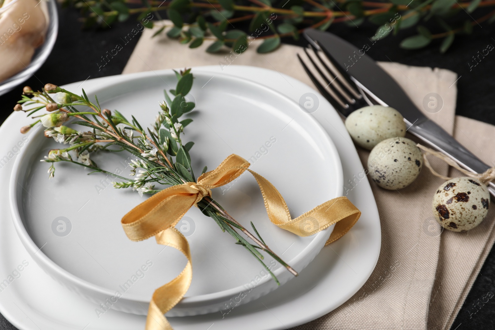 Photo of Festive Easter table setting with eggs and floral decoration on dark background, closeup