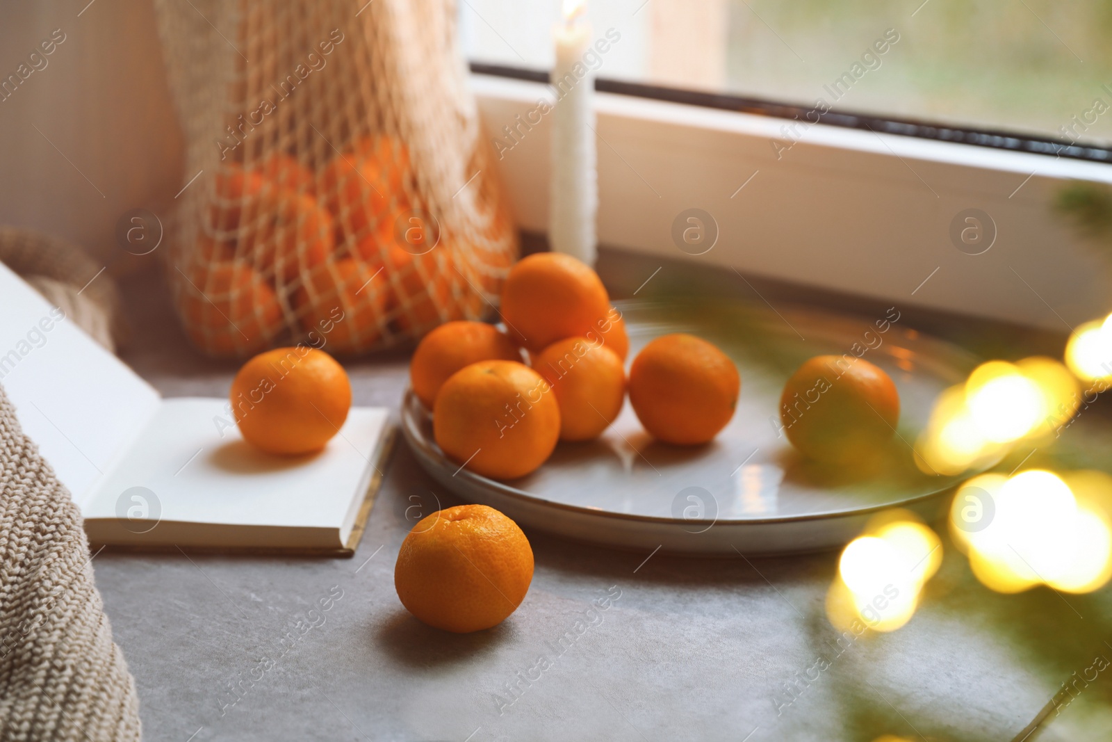 Photo of Fresh ripe tangerines and Christmas decor on grey table near window