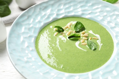 Plate of healthy green soup with fresh spinach on table, closeup