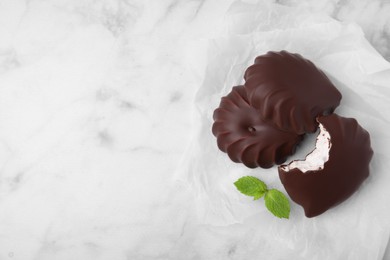 Delicious chocolate covered marshmallows with mint on white marble table, flat lay. Space for text