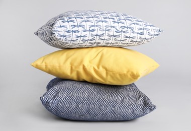 Stack of stylish soft pillows on grey background