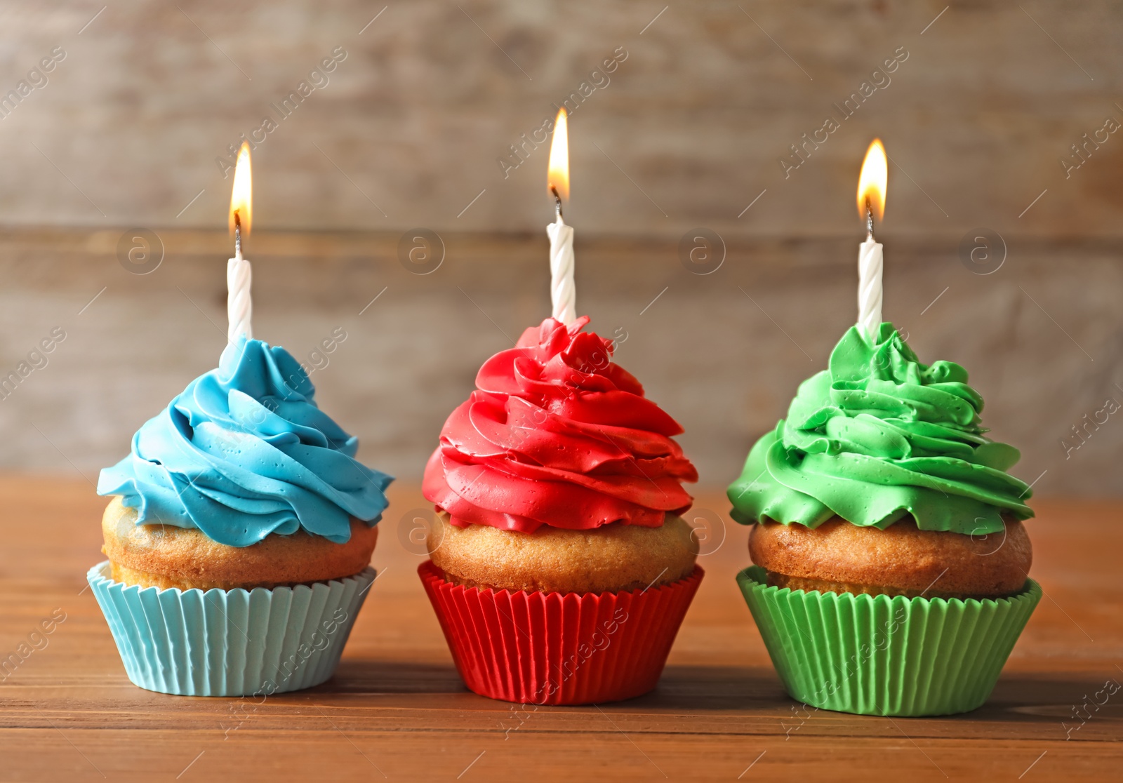 Photo of Delicious birthday cupcakes with candles on table