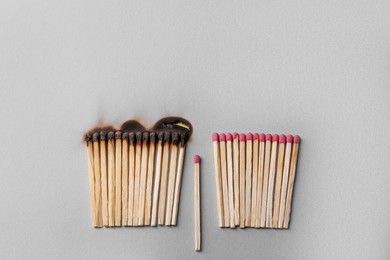 Photo of Burnt and whole matches on light grey background, flat lay. Space for text