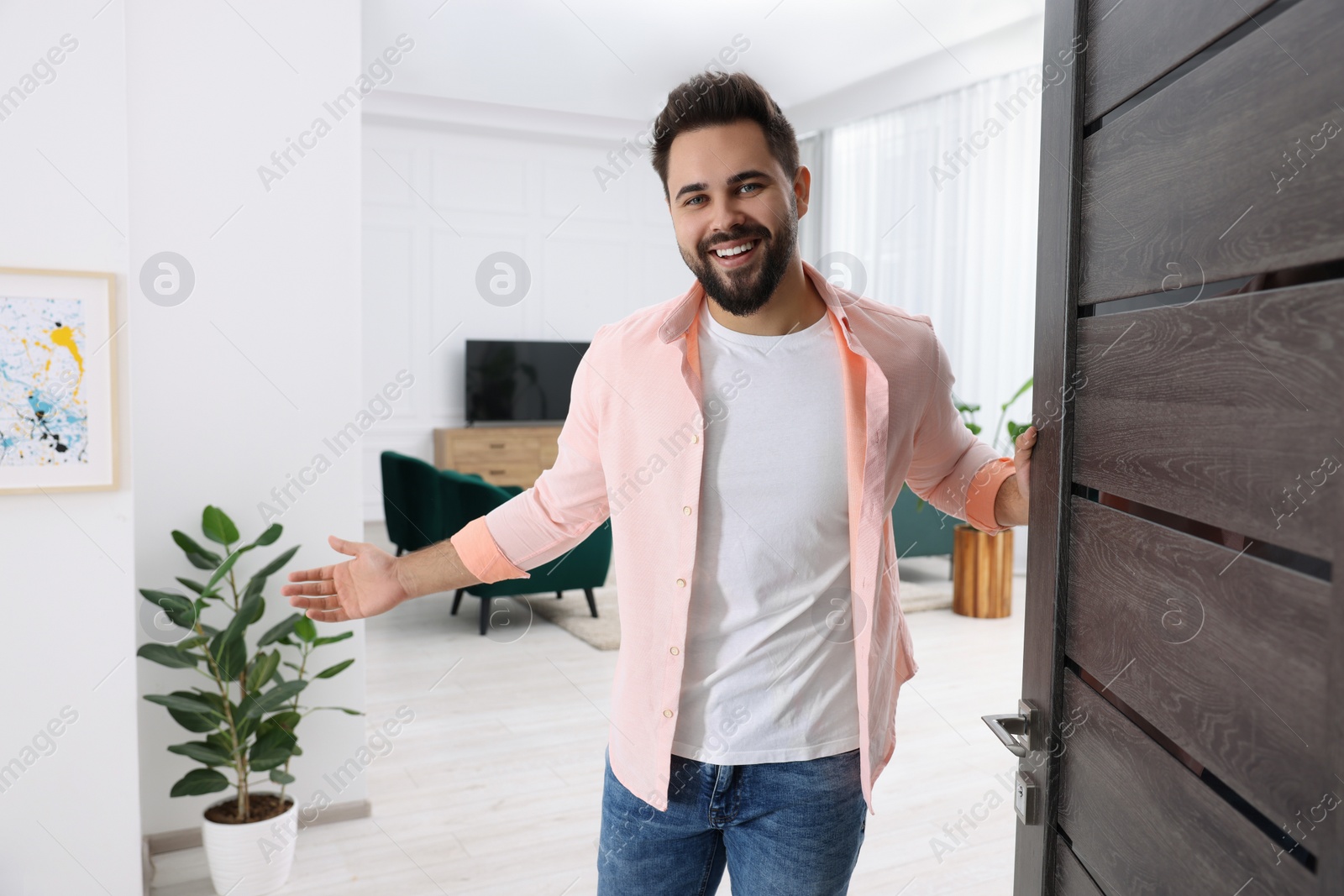 Photo of Happy man welcoming near door. Invitation to come indoors