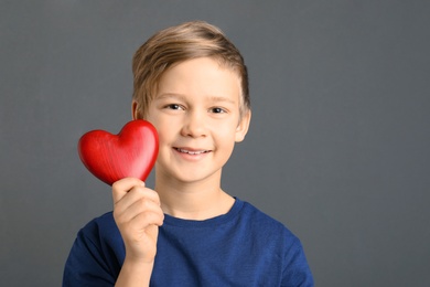 Cute boy holding wooden heart on grey background. Space for text