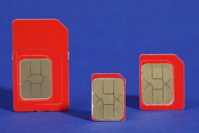 Photo of Different red SIM cards on blue background, closeup