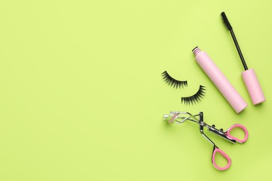 False eyelashes, curler and mascara on light green background, flat lay. Space for text