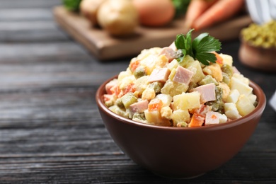 Photo of Delicious salad Olivier on black wooden table, closeup