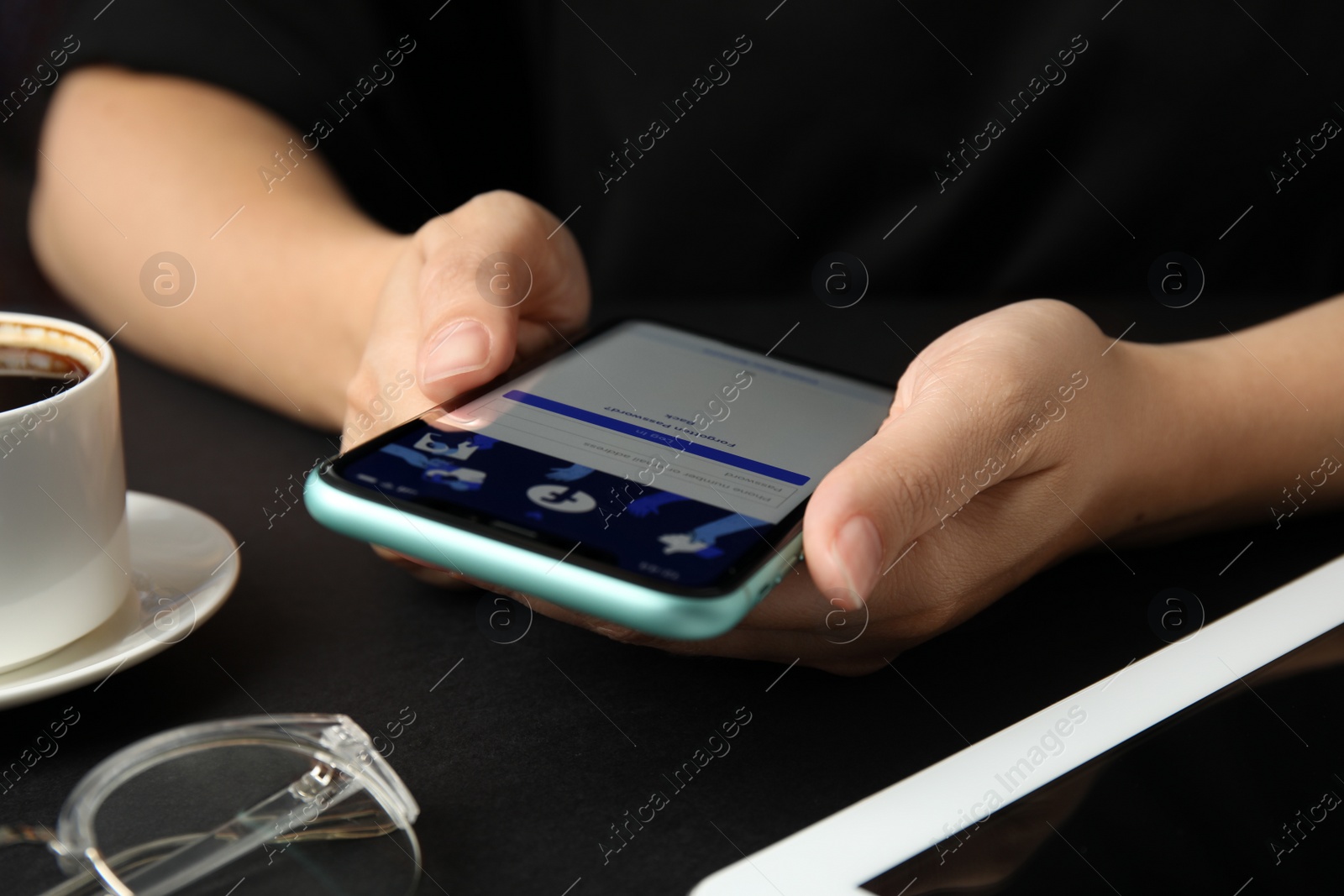 Photo of MYKOLAIV, UKRAINE - JULY 9, 2020: Woman holding Iphone 11 with Facebook app on screen at black table, closeup