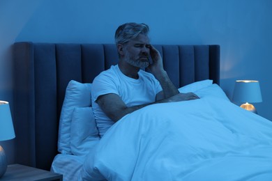 Mature man suffering from headache in bed at night