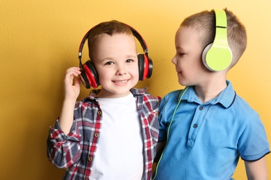 Photo of Portrait of cute twin brothers with headphones on color background