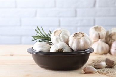 Photo of Fresh raw garlic and rosemary on wooden table