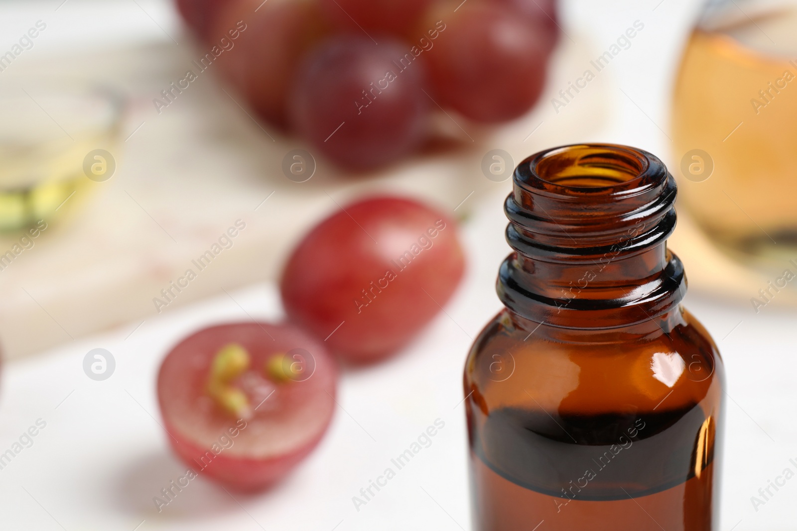 Photo of Natural grape seed oil on white table, closeup. Organic cosmetic