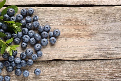 Photo of Tasty fresh blueberries on wooden table, flat lay. Space for text