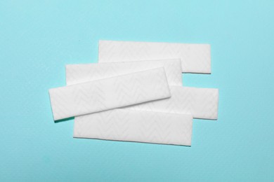 Photo of Sticks of tasty chewing gum on light blue background, flat lay
