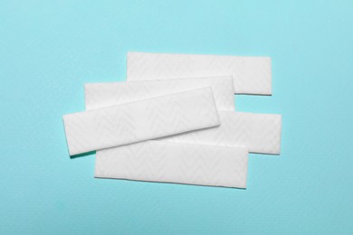 Sticks of tasty chewing gum on light blue background, flat lay