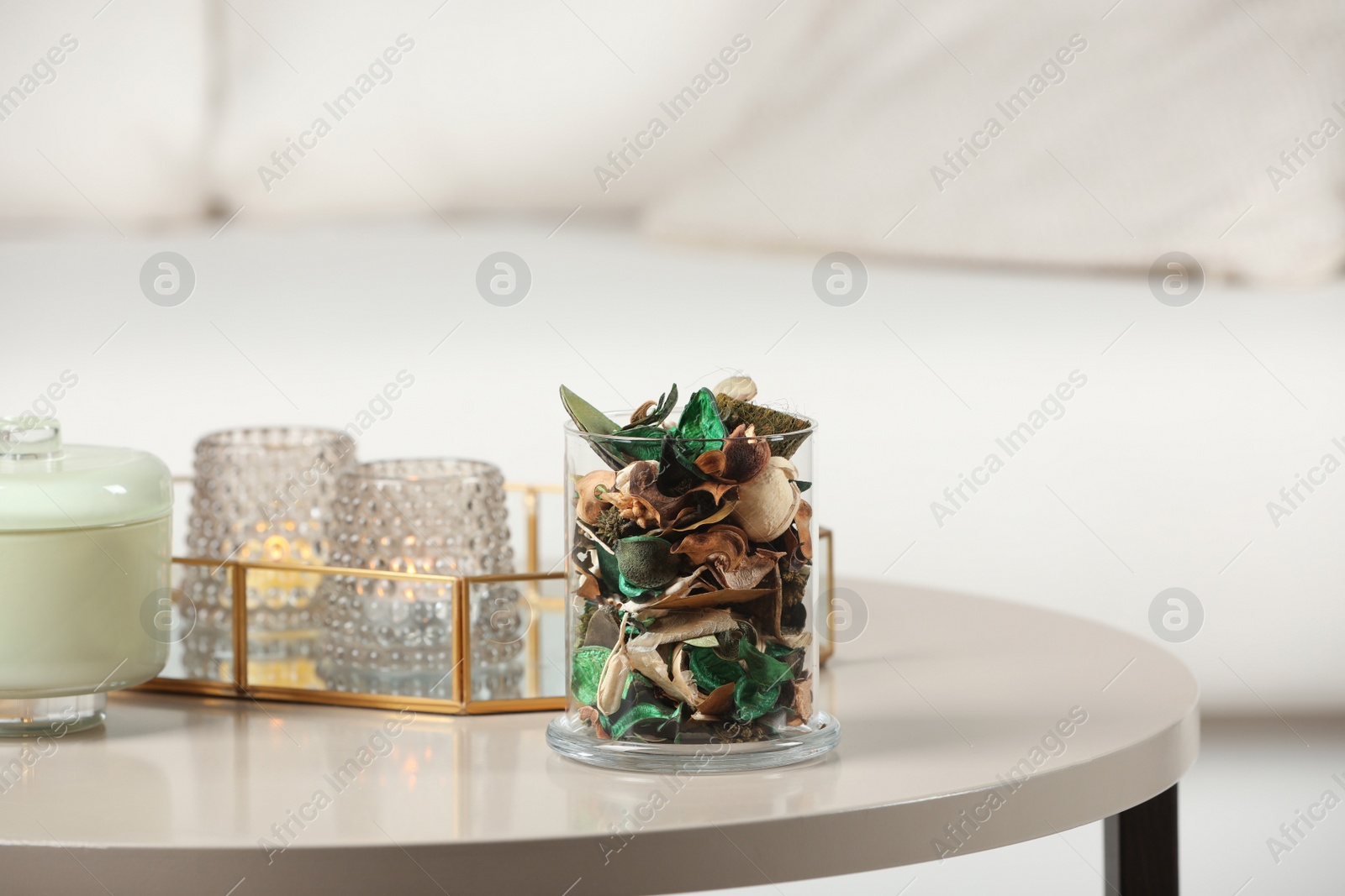Photo of Aromatic potpourri of dried flowers in glass jar on white table indoors