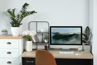 Photo of Comfortable workplace with modern computer, decor and office supplies on wooden table indoors