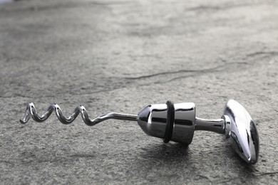 Photo of One metal corkscrew on grey textured table, closeup