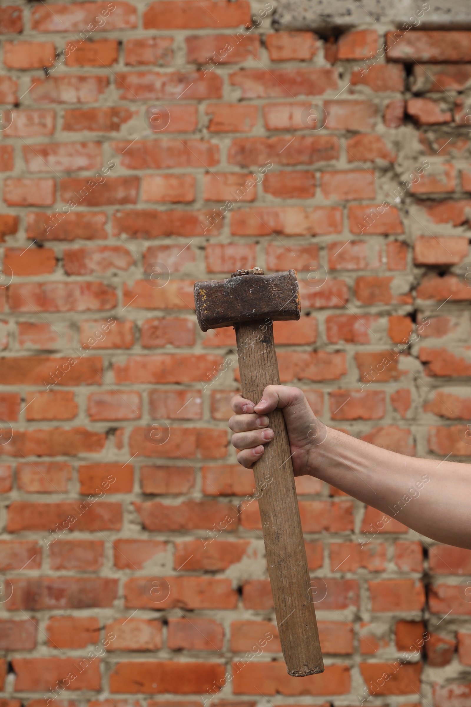 Photo of Man with sledgehammer near brick wall, closeup. Space for text