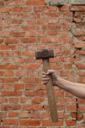 Man with sledgehammer near brick wall, closeup. Space for text