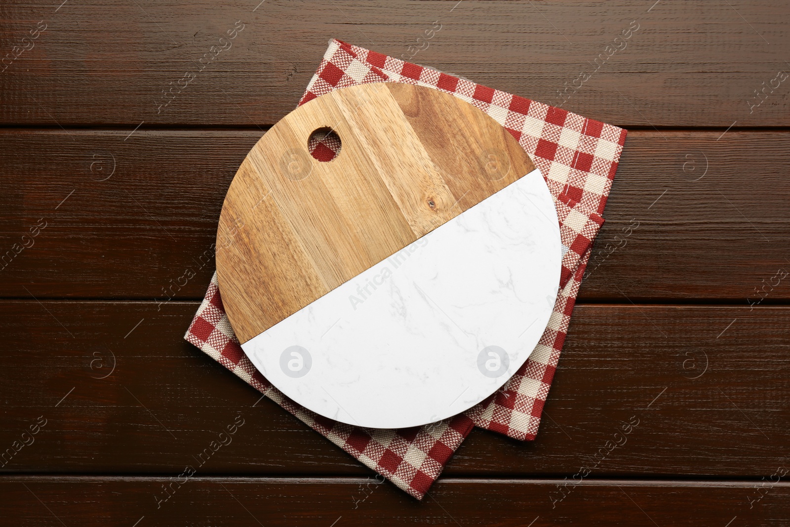 Photo of New cutting board and kitchen towel on wooden table, top view