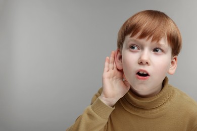 Photo of Little boy with hearing problem on grey background, space for text