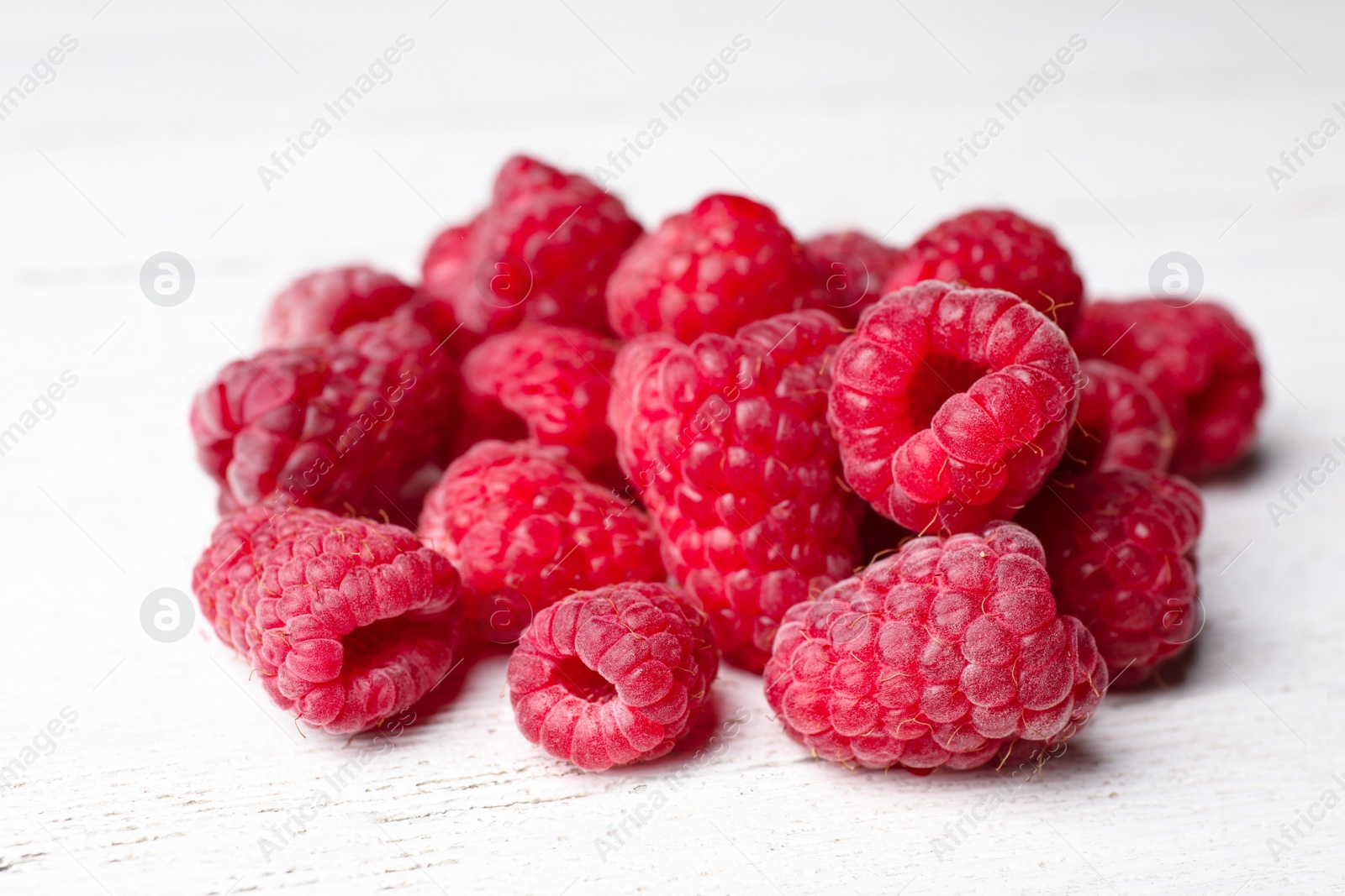 Photo of Heap of delicious ripe raspberries on white wooden table, closeup