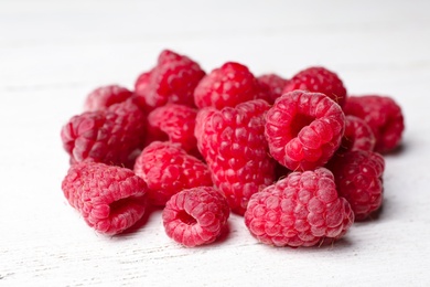 Heap of delicious ripe raspberries on white wooden table, closeup