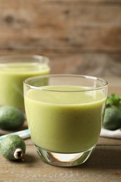 Photo of Fresh feijoa smoothie on wooden table, space for text