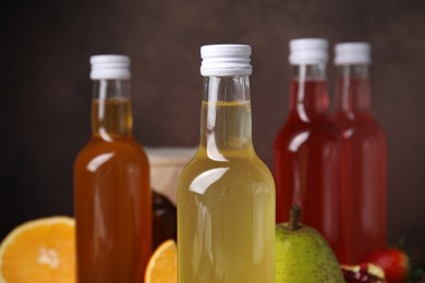 Delicious kombucha in glass bottles and fresh fruits against blurred background