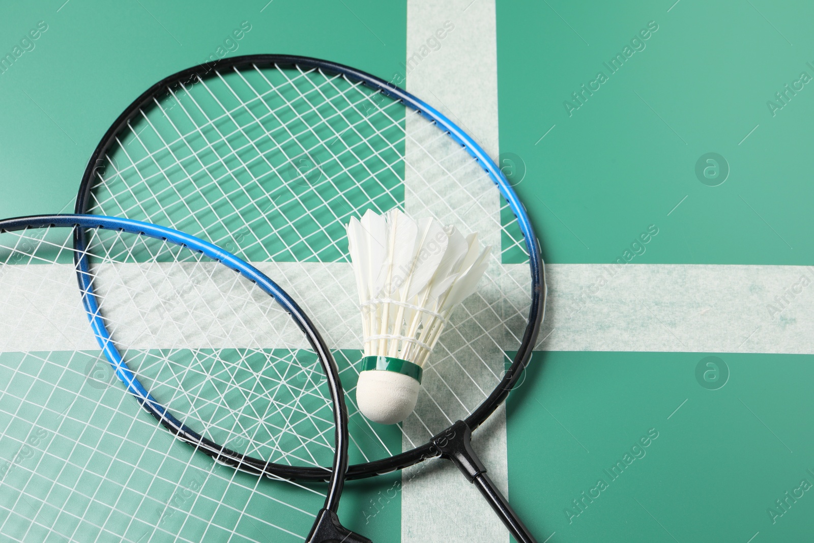 Photo of Feather badminton shuttlecocks and rackets on green table, above view