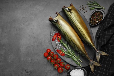 Photo of Delicious smoked mackerels and spices on dark grey table, flat lay. Space for text