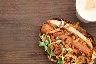Photo of Fresh delicious hot dog and paper cup of coffee on wooden table, flat lay. Space for text