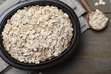 Photo of Bowl and spoon with oatmeal on wooden table, flat lay