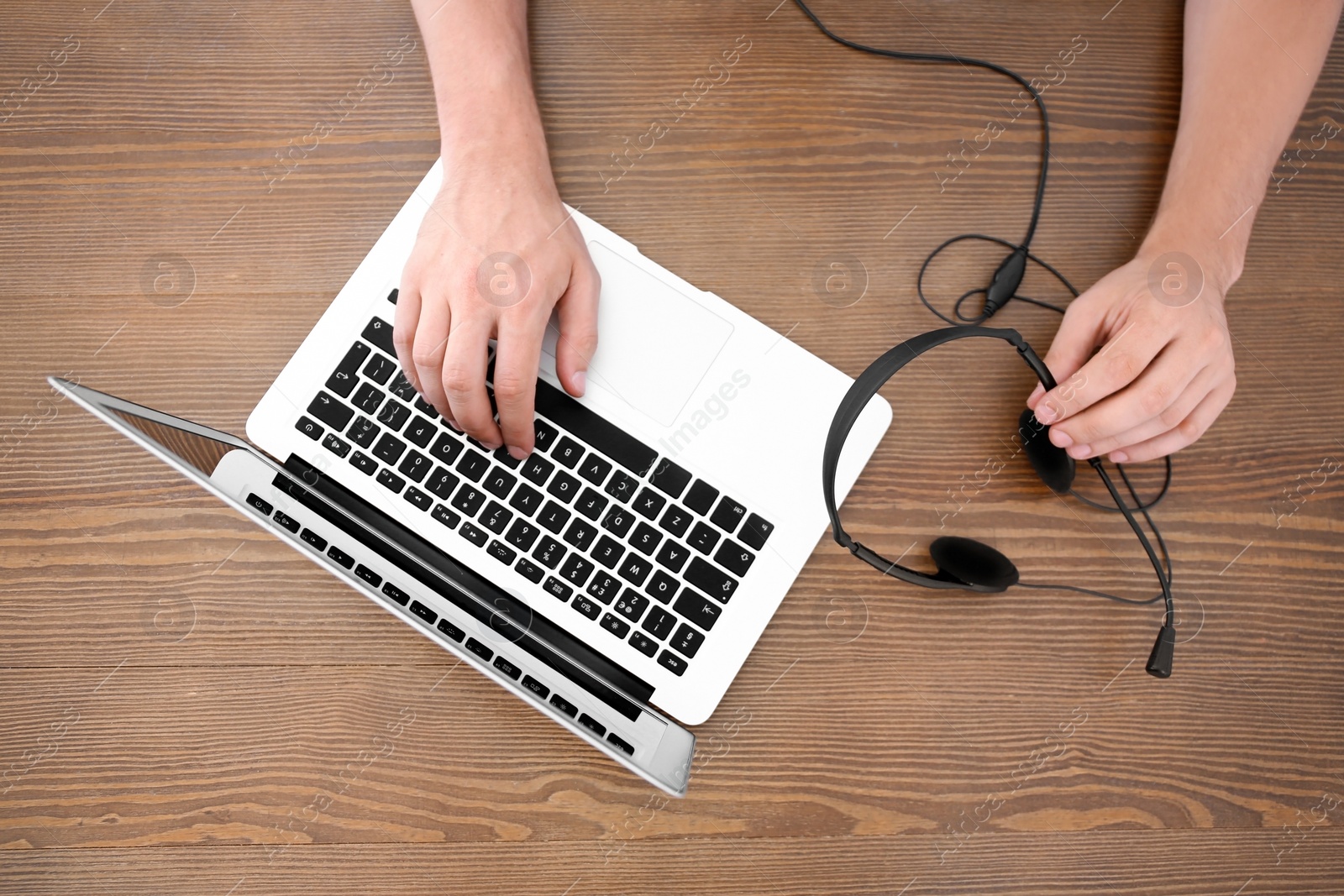 Photo of Male technical support operator with headset and laptop at table, top view