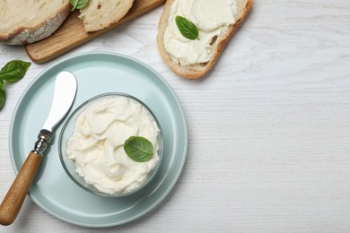 Tasty cream cheese with basil and fresh bread on white wooden table, flat lay. Space for text