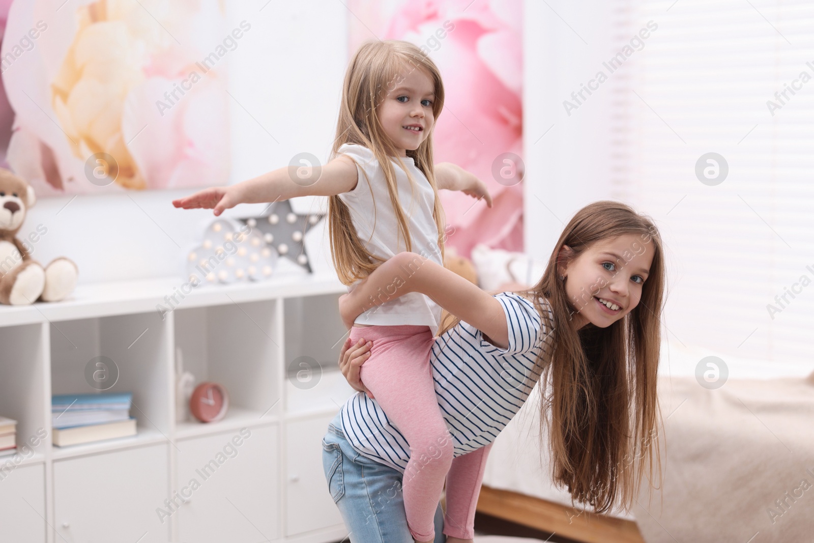 Photo of Cute little sisters having fun together at home