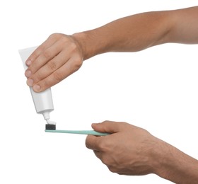Man applying toothpaste on brush against white background, closeup