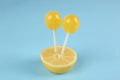 Fresh lemon with yellow lollipops on light blue background