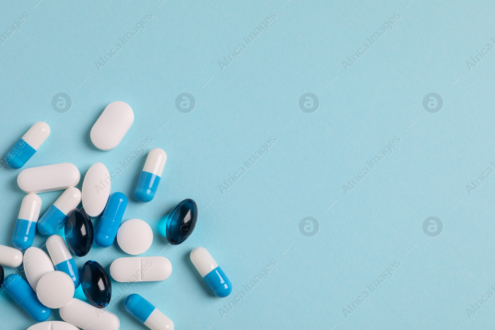 Photo of Many different pills on light blue background, flat lay. Space for text