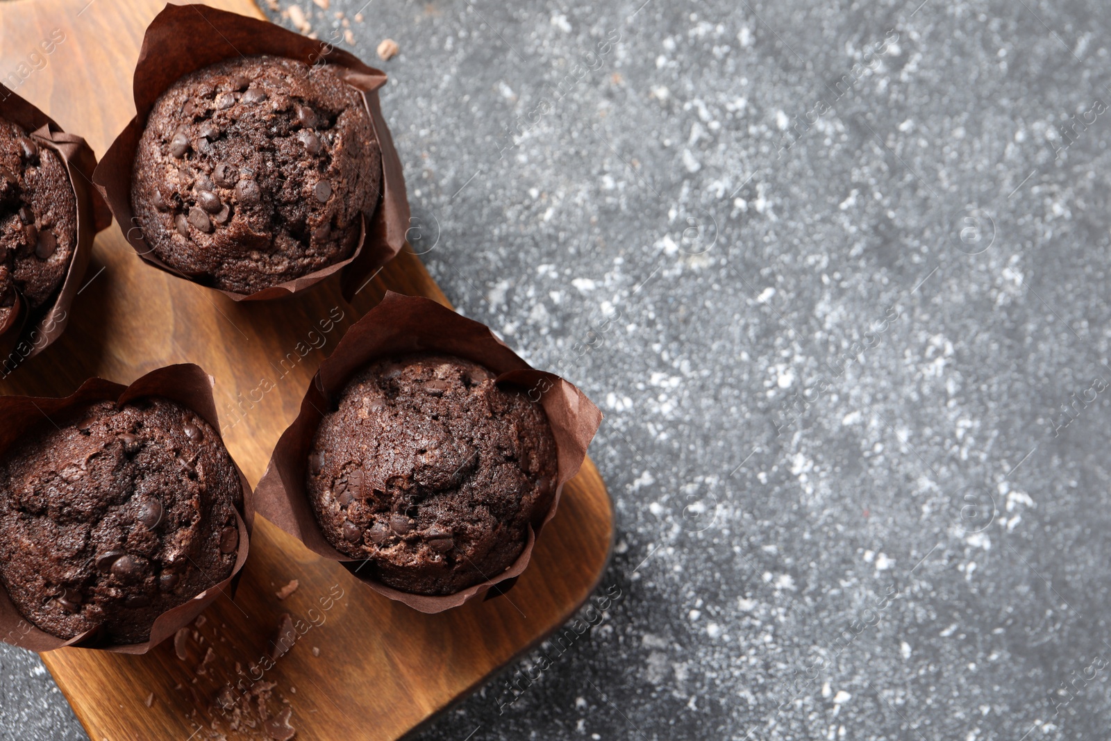 Photo of Tasty chocolate muffins on grey table, top view. Space for text