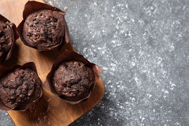 Photo of Tasty chocolate muffins on grey table, top view. Space for text