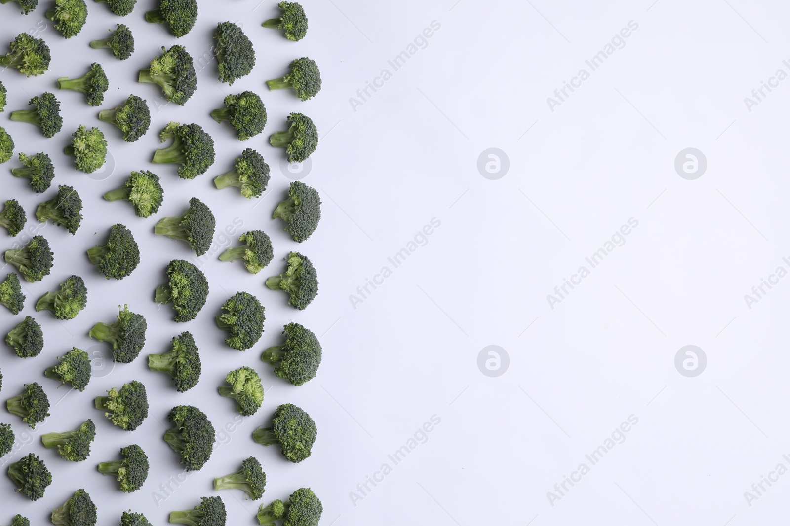 Photo of Many fresh green broccoli pieces on white background, flat lay. Space for text